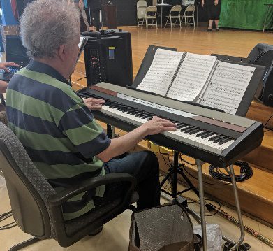 A person using a computer sitting on top of a piano Description automatically generated